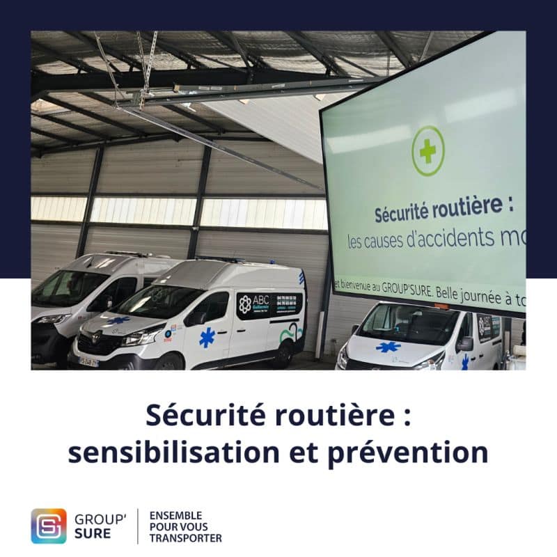 Véhicules sanitaires stationnés dans un garage Group’Sure, avec un écran affichant une campagne de sensibilisation à la sécurité routière.