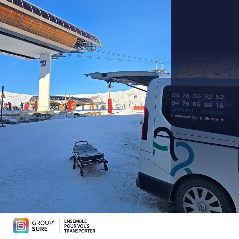 Véhicule sanitaire Group’Sure stationné près des pistes de l’Alpe d’Huez, avec un brancard installé sur la neige.