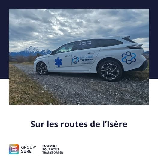 Véhicule sanitaire La Sure Voironnaise stationné sur une route de l’Isère avec vue sur les montagnes enneigées.